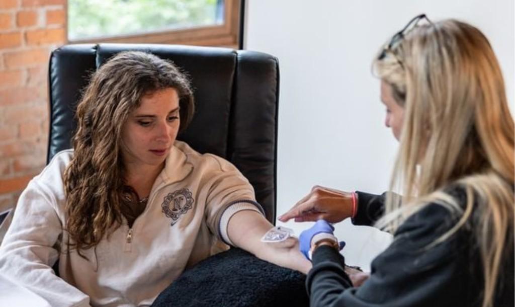 Licensed Drip Lounge nurse providing mobile IV therapy to a client at home